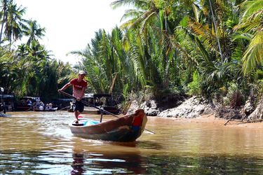 Man rowing a boat among palm trees